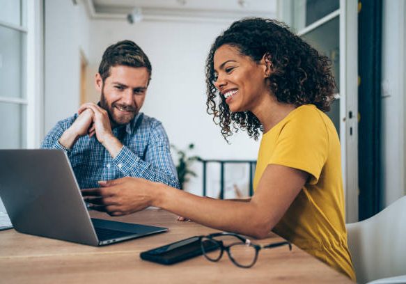 Shot of two successful businesspeople working together on a laptop in modern office. Businessman and businesswoman in meeting using laptop and discussing business strategy. Two business people talking in the office.